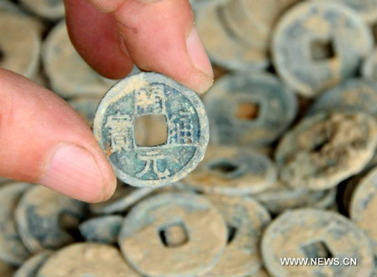 A staff member of the Shahe Administration of Cultural Heritage shows antique coins dating back to ancient China's Tang Dynasty (618-907) in Shahe City, north China's Hebei Province, Aug. 13, 2010. Archeologists recently unearthed about 17,000 antique coins of the Tang Dynasty from a construction site in Shahe.