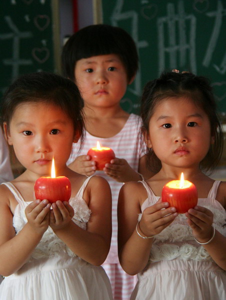 Children at a kindergarten in Tancheng county, Shandong province, hold a candlelight vigil in memory of Zhouqu landslide victims on August 14, 2010.