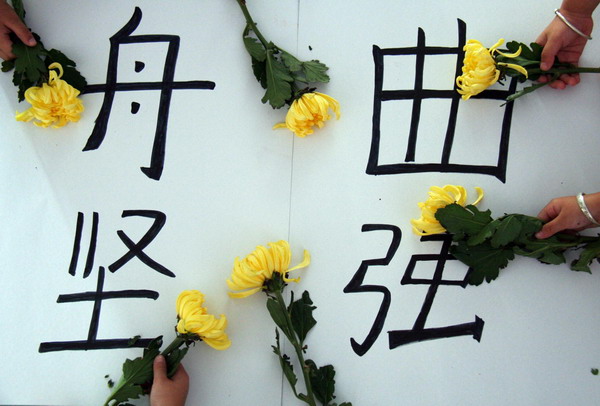 Yellow chrysanthemum flowers are seen at a &apos;Zhouqu, be strong&apos; message during a memorial held by a kindergarten in Tancheng county, Shandong province for Zhouqu landslide victims on August 14, 2010. 