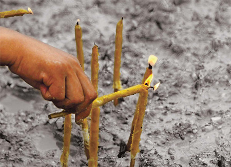 A resident burns incense for people killed by a mudslide in Zhouqu County, Gansu Province. 