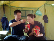 A couple having noodle in their temporary settlement landslide-hit area Zhouqu on August, 16, 2010. [Xinhua]