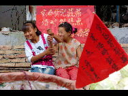 Two girls are seen with smile in landslide-hit area Zhouqu on August, 13, 2010. [Xinhua]