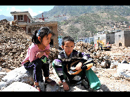 Wang Jinyan, 8, and her brother, Wang Jinhong, 10, sit in front of the ruins of their school building in Zhouqu on Aug 15, worrying that they cannot go to school again. They are students from No 1 Primary School in Zhouqu. [Xinhua]