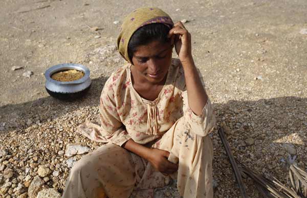 A woman fleeing from floodwaters sits with her food handout while taking refuge on a mound in Sukkur, in Pakistan&apos;s Sindh province August 16, 2010. Pakistan authorities forecast on Monday a brief respite in rains that sparked the country&apos;s worst floods in decades, but aid agencies warned help was too slow to arrive for millions without clean water, food and homes. [Xinhua/Reuters]