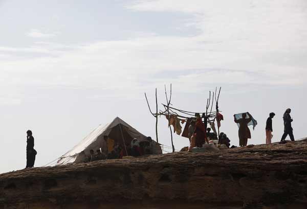 A family takes refuge from flood waters on a mound in Sukkur in Pakistan&apos;s Sindh province August 16, 2010. Pakistan authorities forecast on Monday a brief respite in rains that sparked the country&apos;s worst floods in decades, but aid agencies warned help was too slow to arrive for millions without clean water, food and homes. [Xinhua/Reuters] 