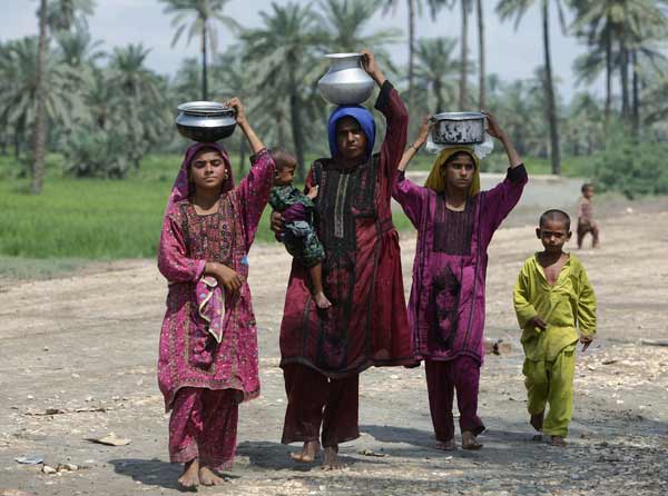 Flood victims carry pots of water filled at a nearby pump on their heads while taking refuge at a roadside makeshift relief camp in Sukkur, in Pakistan&apos;s Sindh province August 16, 2010. Pakistan authorities forecast on Monday a brief respite in rains that sparked the country&apos;s worst floods in decades, but aid agencies warned help was too slow to arrive for millions without clean water, food and homes.[Xinhua/Reuters]