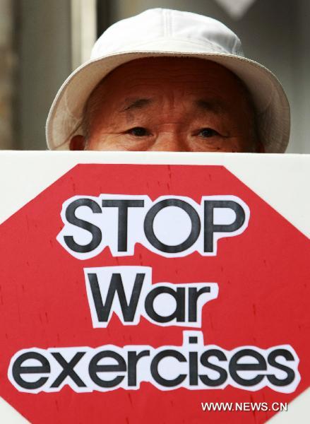A demonstrator holds a placard during a protest against the South Korea-U.S. joint military exercise, codenamed &apos;Ulchi Freedom Guardian&apos;, in front of the South Korean-U.S. War Command Center TANGO in Seongnam, South Korea, on Aug. 16. 2010. South Korea and the U.S. began the two-week joint military exercise on Aug. 16.[Park Jin-hee/Xinhua]