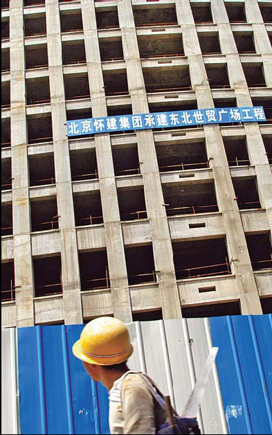 A worker walks past a building under construction in Shenyang, Liaoning province. [China Daily]