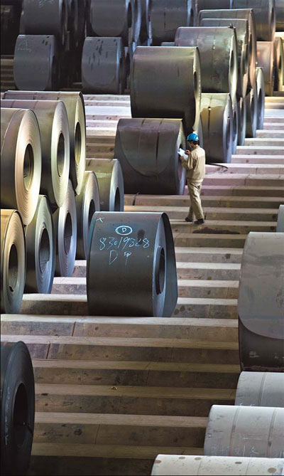 A worker inspects flat-rolled steel at Wuhan Steel. [China Daily]