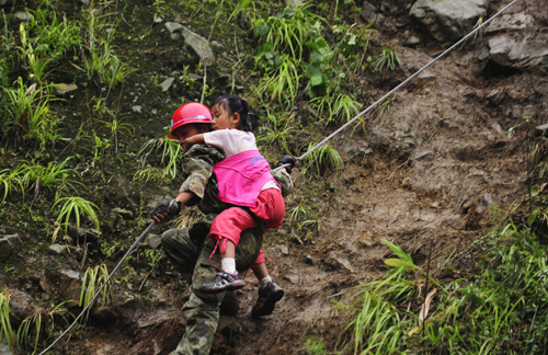 A rescuer helps a girl trapped by landslides in Yingxiu, Southwest China&apos;s Sichuan province on August 17, 2010. [Xinhua] 