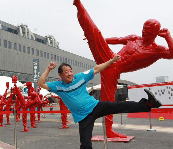  A tourist poses for photos in front of kungfu fighter statues at Expo Park, Aug 17, 2010. [Xinhua] 