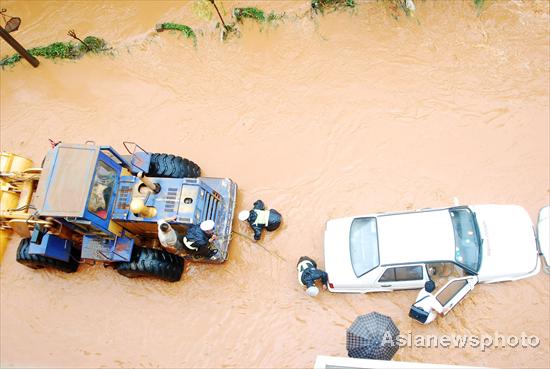 Policemen help people get out of stranded cars on a flooded street in Kunming, capital of Yunnan province, Aug 15, 2010. 
