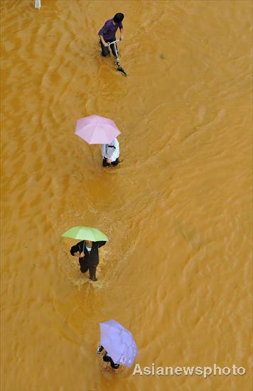 People walk through floodwater in Kunming, capital of Yunnan province, Aug 15, 2010.