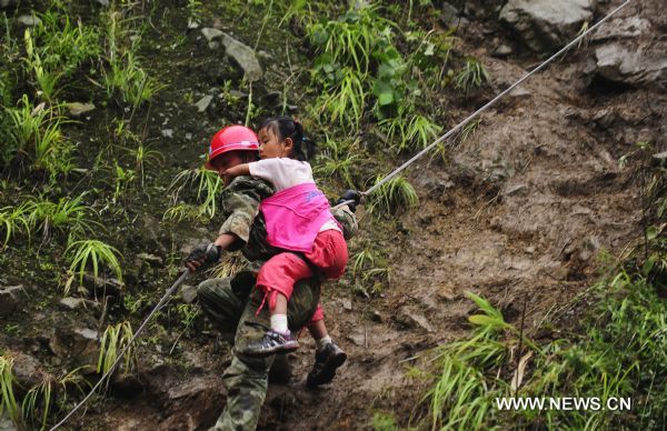 A soldier carries a child to help her get down a slope to a safe place in Yongxiu Town, Wenchuan County, southwest China's Sichuan Province, Aug. 17, 2010. Heavy rain triggered landslides in several towns of Wenchuan County Aug. 14, where an 8-magnitude earthquake claimed almost 70,000 lives on May 12, 2008. 