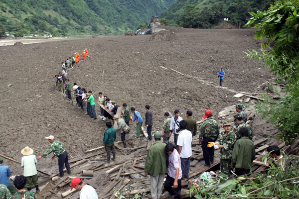 Residents and soldiers help people trapped by the mudslide in Yunnan on Aug 18. [Xinhua]