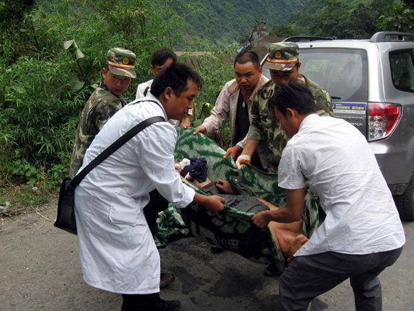 Soldiers and doctors help an injured resident after a mudslide in Yunnan on Aug 18. [Xinhua]