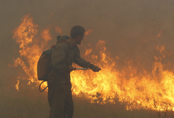 A firefighter attempts to extinguish fire outside the town of Shatura, some 110 km southeast of Moscow, August 12, 2010. [Xinhua]