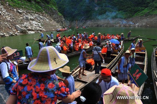Tourists board the wooden boats towed by boat trackers in Shennongxi Canyon, a famous tourist resort of the Three Gorges scenic area, in Badong County, central China's Hubei Province, Aug. 17, 2010. Over 700 boat trackers are working in the canyon at present to showcase the time-honored boat-tracker culture. [Xinhua/Zhang Xiaofeng]