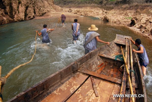 The file photo taken in June 2009 shows boat trackers towing a wooden boat in water in Shennongxi Canyon, a famous tourist resort of the Three Gorges scenic area, in Badong County, central China's Hubei Province. Over 700 boat trackers are working in the canyon at present to showcase the time-honored boat-tracker culture. [Xinhua/Zhang Xiaofeng]