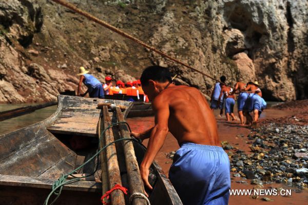 Boat trackers tow the wooden boat forward in Shennongxi Canyon, a famous tourist resort of the Three Gorges scenic area, in Badong County, central China's Hubei Province, Aug. 17, 2010. Over 700 boat trackers are working in the canyon at present to showcase the time-honored boat-tracker culture. [Xinhua/Zhang Xiaofeng]