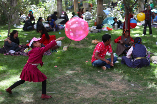 A girl plays on the grassland where throngs of visitors sit for rest.Zhang Tao / China Daily