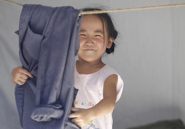 A girl arranges her father&apos;s coat in a makeshift tent in mudslide-hit Zhouqu county, Northwest China&apos;s Gansu province, Aug 19, 2010. [Xinhua]