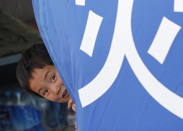 A girl plays in a makeshift tent in mudslide-hit Zhouqu county, Northwest China&apos;s Gansu province, Aug 19, 2010. [Xinhua]