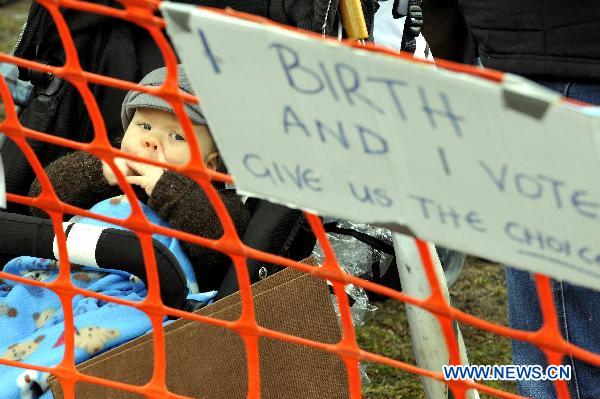 A baby is seen during a protest as Australian Prime Minister Julia Gillard delivers her speech at the National Press Club in Canberra, capital of Australia, on Aug. 19, 2010. [Huang Xiaoyong/Xinhua]