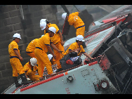 Workers take out luggages and belongings of passengers from a damaged carriage off the Baoji-Chengdu Railway in Xiaohan Township of Guanghan city, southwest China's Sichuan Province, Aug. 20, 2010. The railway between Baoji, a city of China's Shaanxi Province, and Chengdu, capital of China's Sichuan Province, was reconnected Friday by an alternative railway though a railway bridge on its Guanghan part was destroyed by floods on Thursday. [Jiang Hongjing/Xinhua]