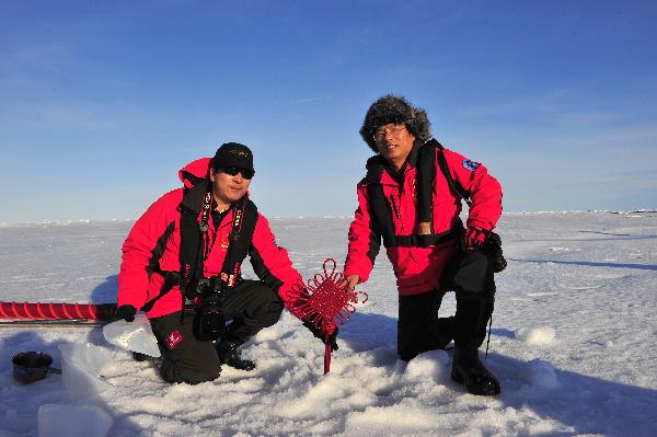 Wu Jun (L), the crew leader of the fourth Chinese scientific expedition team, and Yu Xingguang, a scientist, pose for a group photo with a Chinese knot at the North Pole, Aug. 20, 2010. The Chinese fourth expedition team arrived at the North Pole on 15:38 p.m. (0738 GMT) Friday, which is the northernmost location ever reached by Chinese scientific expeditions.[Zhang Jiansong/Xinhua]