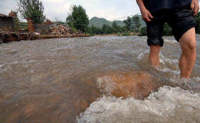 A villager walks in flooded road at Tuanjie Village, Kuandian Man Autonomous County of Dandong City, northeast China's Liaoning Province, Aug. 21, 2010. 