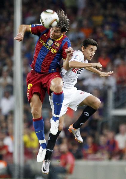 Barcelona&apos;s Maxwell (L) jumps for the ball against Sevilla&apos;s Jesus Navas during their Spanish Super Cup second leg soccer match at Nou Camp stadium in Barcelona August 21, 2010. 