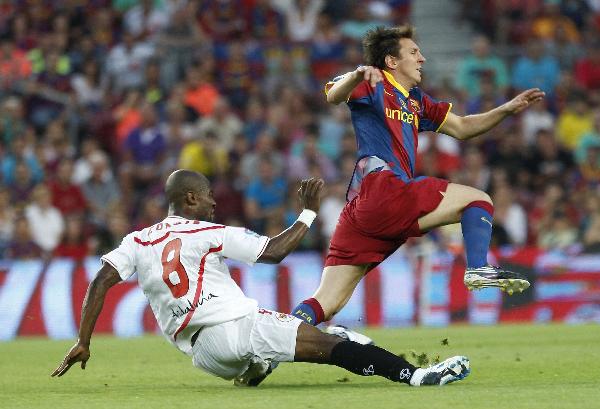 Barcelona's Lionel Messi (R) is tackled by Sevilla's Didier Zokora during their Spanish Super Cup second leg soccer match at Nou Camp stadium in Barcelona August 21, 2010. 