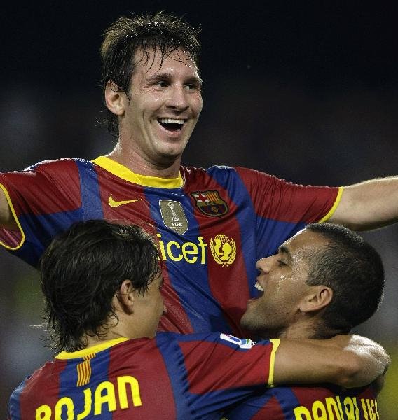 Barcelona&apos;s Lionel Messi (top) celebrates his goal with Bojan Krkic (L) and Dani Alves during their Spanish Super Cup second leg soccer match against Sevilla in Barcelona August 21, 2010. 