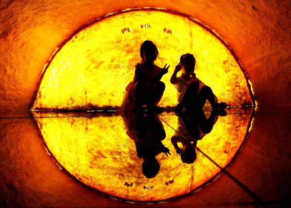 Two children pose for photos in front of the picture simulating centrosphere at the Nanjing Geological Museum in Nanjing, capital of east China&apos;s Jiangsu Province, Aug. 22, 2010. The Nanjing Geological Museum opens to the public free of charge during the summer vacation, attracting lots of citizens to learn about the knowledge of geological disasters. [Xinhua]