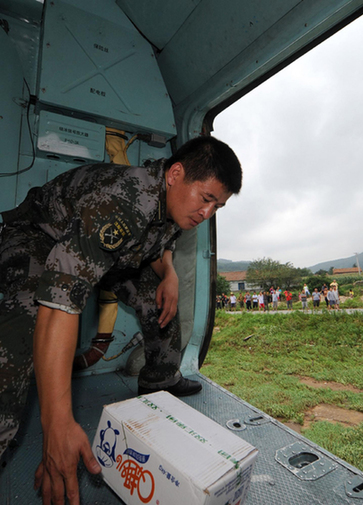 A soldier drops a box of food to a flooded village in Dandong on August 22, 2010. [Xinhua] 