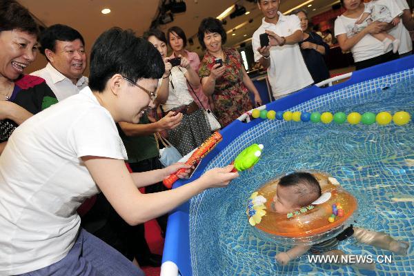 A baby reacts in the final of a swimming competition for babies of 0-3 years of age in Hangzhou, capital of east China&apos;s Zhejiang Province, Aug. 22, 2010. [Xinhua]