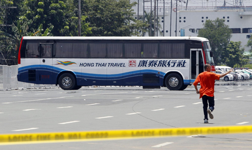 A hostage negotiator runs towards a tourist bus containing passengers taken hostage by a former police officer in Manila August 23, 2010. [Agencies]
