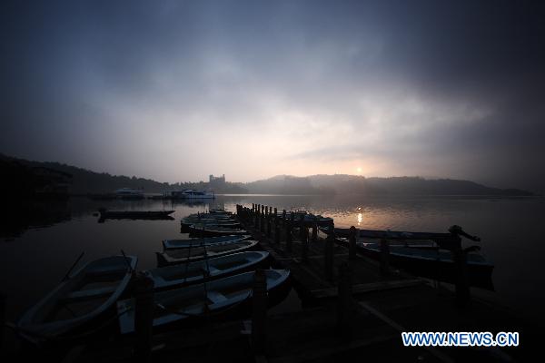 Boats are seen at a dock in Riyue Tan, or the Sun Moon Lake, southeast China's Taiwan, at dawn on Aug. 22, 2010. [Xinhua/Fei Maohua]