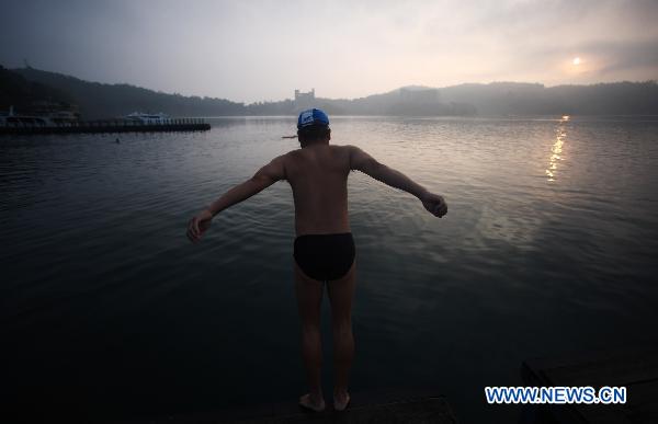 A man tries to dive into Riyue Tan, or the Sun Moon Lake, southeast China's Taiwan, at dawn on Aug. 22, 2010. [Xinhua/Fei Maohua]