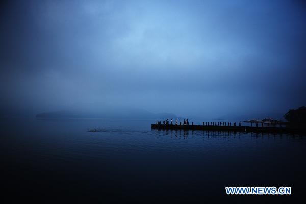 People start their morning exercises on a dock in Riyue Tan, or the Sun Moon Lake, southeast China's Taiwan, at dawn on Aug. 22, 2010. [Xinhua/Fei Maohua]