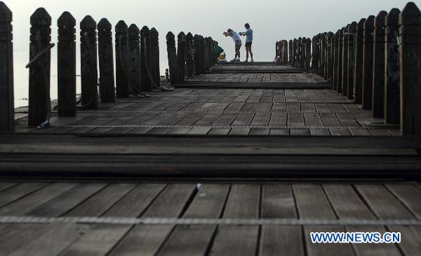 People take exercises on a dock in Riyue Tan, or the Sun Moon Lake, southeast China's Taiwan, at dawn on Aug. 22, 2010. [Xinhua/Fei Maohua]