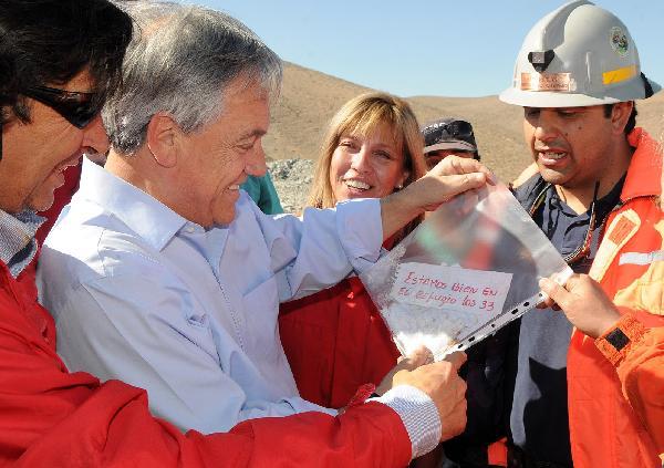 Chilean President Sebastian Pinera (L) holds a note reading 'we are fine in the shelter, the 33 of us' from the 33 miners trapped in a copper mine near Copiapo in north Chile, Aug. 22, 2010. Pinera said on Sunday that the 33 miners trapped since Aug. 5 in a copper mine are still alive. [Chilean Presidential Service/Xinhua]