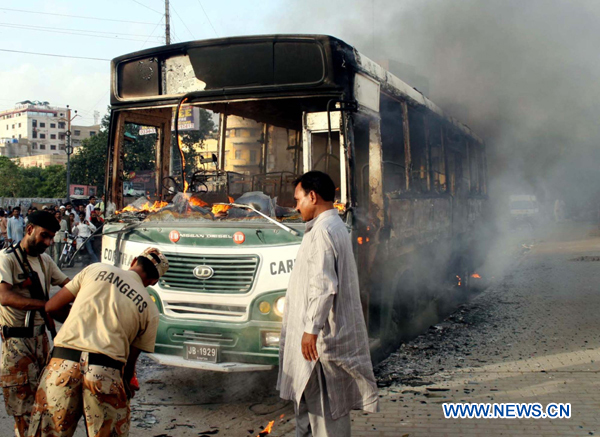 People gather near the wreckage of a bus after a protest against a target killing in southern Pakistan&apos;s Karachi, Aug. 22, 2010. (Xinhua/Arshad)