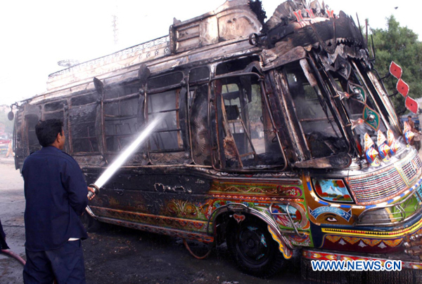 A man tries to put out a burning bus after a protest against a target killing in southern Pakistan&apos;s Karachi, Aug. 22, 2010. (Xinhua/Arshad)