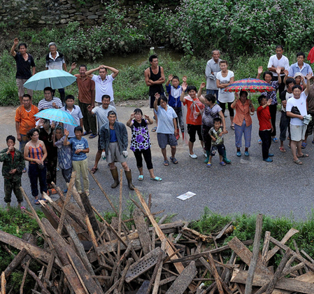 Villagers wave to soldiers who drop food above on two helicopters in Hushan county, Dandong on August 22, 2010. Floods hit Hushan on Saturay, cutting the county's transportation routes. [Photo/Xinhua]