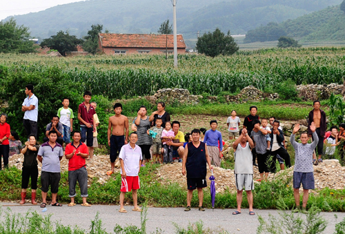 Villagers wave to soldiers who drop food above on two helicopters in Hushan county, Dandong on August 22, 2010. [Photo/Xinhua]