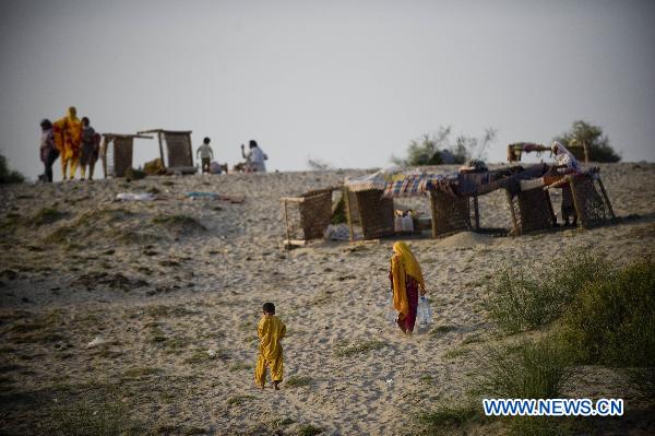 Flood refugees walk past self-built tents near Muzaffargarh, south Pakistan&apos;s Punjab Province, Aug. 23, 2010. UN estimated that the continuing month-long floods have caused 280 million dollars losses, rendered 20 million homeless as over 893,000 homes were destroyed across Pakistan where 25 percent of country&apos;s 803.940 square kilometers total landmass is under floodwater. [Xinhua]