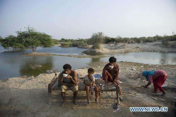 Flood refugee eat food at waterside near Muzaffargarh, south Pakistan&apos;s Punjab Province, Aug. 23, 2010. [Xinhua]