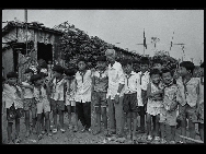 Children of migrant workers stand in front of their school built in the shelter with their teacher (middle) in 1996. [QQ.com] 